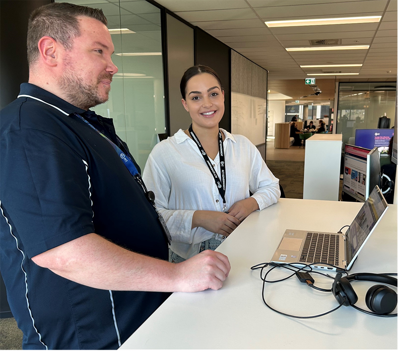 Two contact centre staff standing next to each other at a desk