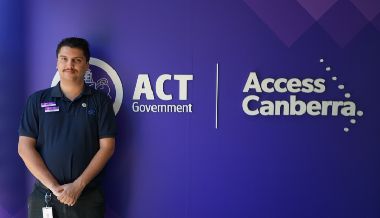 Access Canberra service centre employee standing in front of an Access Canberra sign