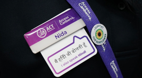 An Access Canberra name badge, displaying the team member's name and the language that they speak in addition to English.